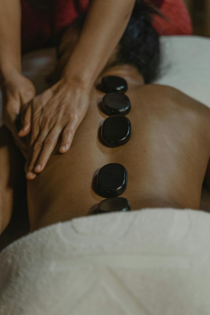 Hot Stone Massage in Glasgow. This image features a lady with hot stones laid on her back and being massaged. 