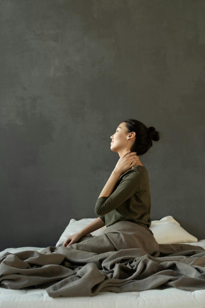 Massage therapy in Glasgow, Scotland. This image features a lady holding her neck in pain. It illustrates poor posture and sleeping wrong. 